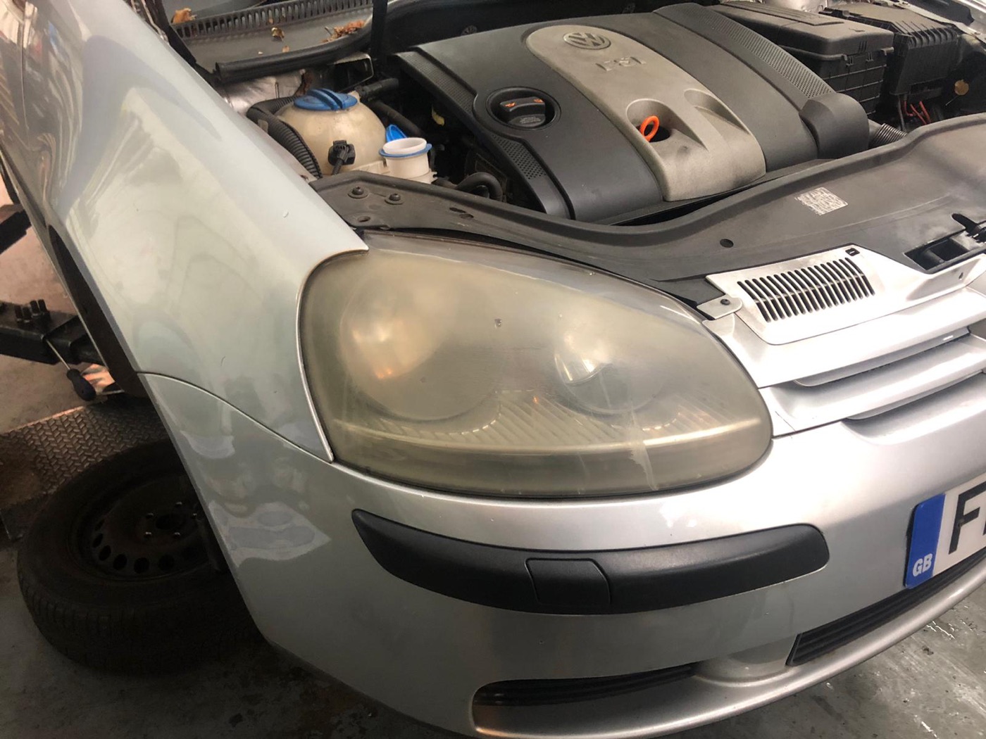 Close-up of a Volkswagen engine bay and headlight during inspection at Witan Motors.