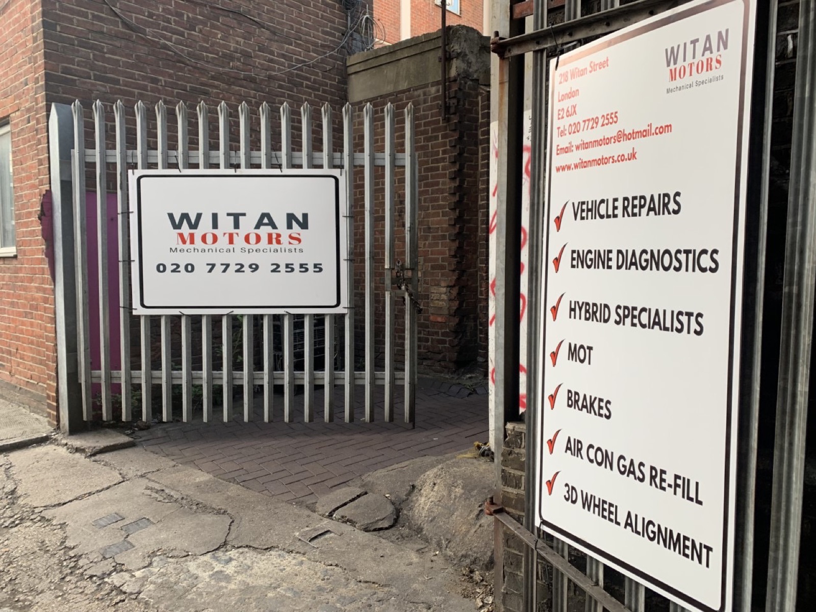 The Witan Motors signage at the railway-arch entrance on Witan Street, listing vehicle repairs, engine diagnostics, hybrid specialists, MOT, brakes, air-con and 3D wheel alignment.