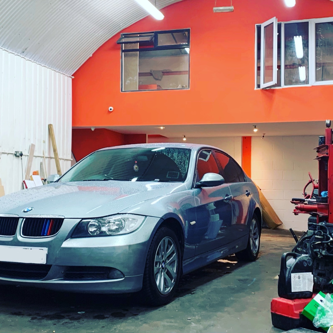 A silver BMW 3 Series in the bay at Witan Motors, beneath the workshop's arched roof and orange feature wall.
